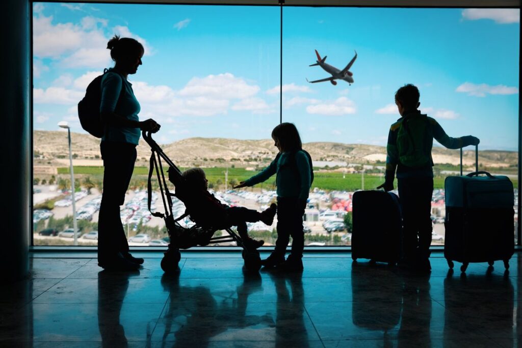 Parents and children waiting at a departure gate with luggage.